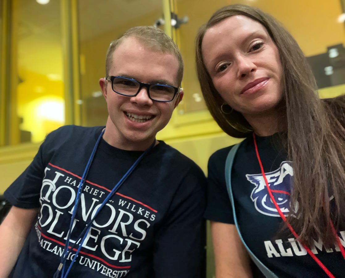 Ryleigh Newman and his mother taking a close selfie at FAU orientation, both wearing navy shirts and lanyards, his reading Honors College and hers reading FAU Alumni.