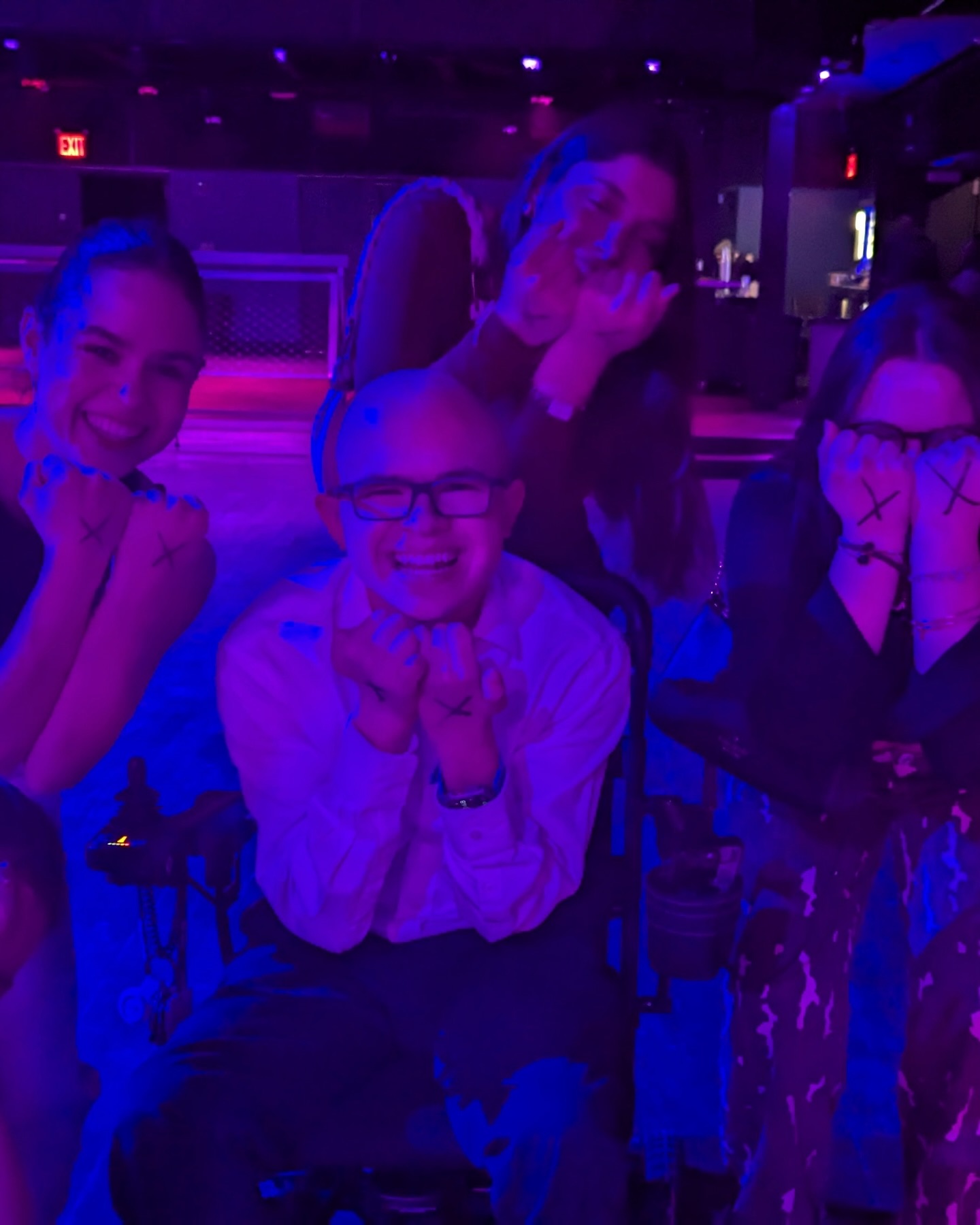 Ryleigh Newman and several other delegates in a dim room lit blue and purple at an evening delegate dance, everyone smiling toward the camera.
